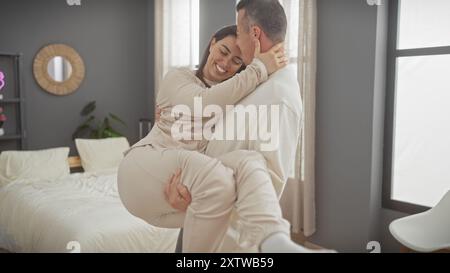 Ein liebevolles Paar umarmt sich herzlich in ihrem gemütlichen Schlafzimmer und schafft eine wunderschöne, intime Szene der Zuneigung. Stockfoto