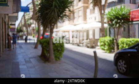 Urbane Outdoor-Szene mit verschwommenen Menschen und Autos auf einer belebten Straße mit Bäumen und Cafés im Hintergrund an einem sonnigen Tag Stockfoto