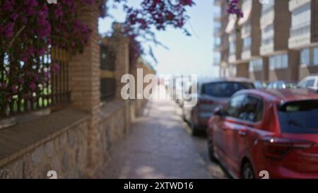 Defokussierte Straßenszene im Freien mit geparkten Autos und lebendigen Blumen, die an einem sonnigen Tag eine verschwommene urbane Umgebung einfangen. Stockfoto