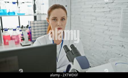 Eine fokussierte junge Wissenschaftlerin, die Proben in einem hellen Laborraum analysiert. Stockfoto