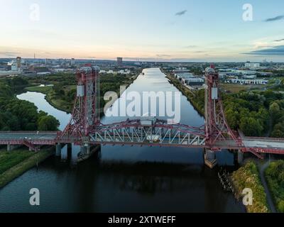 Aus der Vogelperspektive einer roten Brücke mit vertikalem Aufzug über einen Fluss bei Sonnenuntergang, die gateshead und newcastle upon tyne verbindet Stockfoto