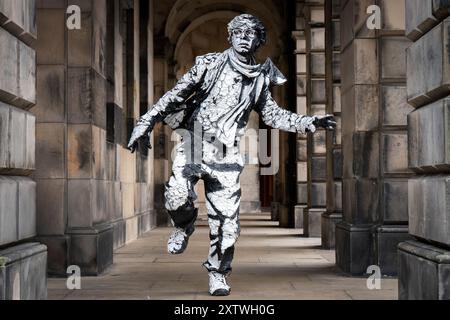 Der aus Ecuador stammende Künstler Estevan Mortensen tritt während des Edinburgh Fringe Festivals als „lebende Statue“ auf der Royal Mile auf. Seine „menschliche Schablone“-Figur ist von dem Straßenkünstler Banksy inspiriert. Bilddatum: Freitag, 16. August 2024. Stockfoto