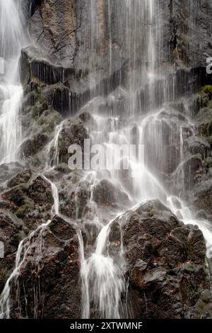 Wasser stürzt über eine felsige Klippe und schafft eine ruhige Wasserfallszene. Stockfoto