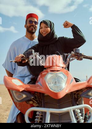 Lächelndes Paar mit Motorrad auf offener Straße, die Frau trägt einen Hijab und der Mann trägt eine Mütze und Sonnenbrille. Stockfoto