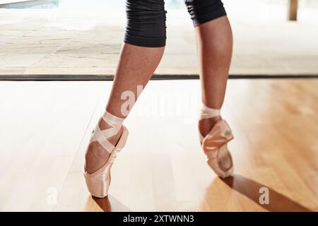 Nahaufnahme der Füße einer Ballerina en pointe mit Ballettschuhen auf Holzboden, mit unscharfem Hintergrund und Pool. Stockfoto