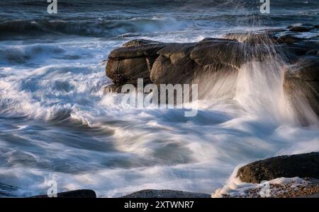 Eine dynamische Meereslandschaft, die Wellen erfasst, die gegen felsige Küsten krachen und Wasser spritzen Stockfoto