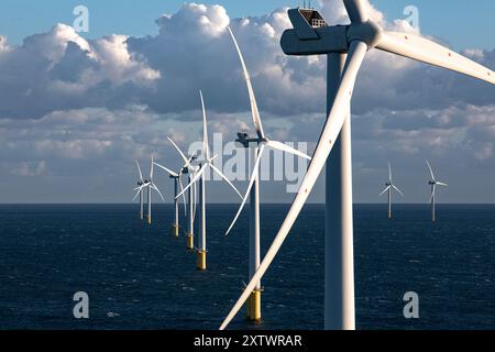 Offshore-Windturbinen stehen hoch über dem Meer unter bewölktem Himmel. Stockfoto