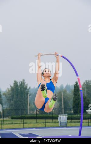 Eine Sportlerin, die einen Hochsprung über einer Bar bei einem Outdoor-Leichtathletik-Event durchführt. Stockfoto