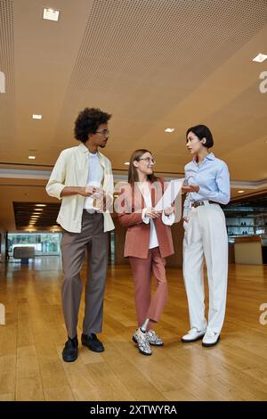 Drei Kollegen stehen in einem modernen Büroumfeld zusammen und führen eine lebhafte Diskussion. Stockfoto