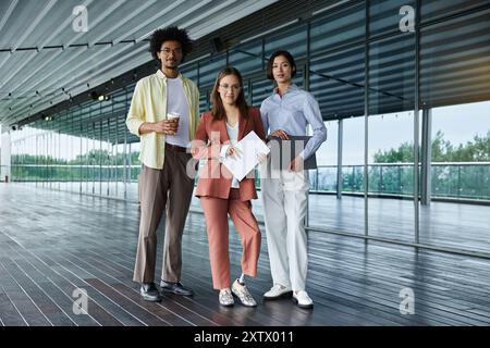 Drei Kollegen mit unterschiedlichen ethnischen Zugehörigkeiten und Fähigkeiten stehen auf einer modernen Dachterrasse des Büros zusammen und genießen eine Pause und ein Gespräch. Stockfoto