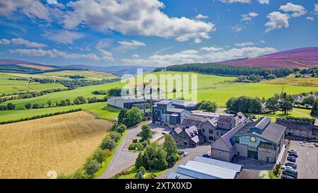 Die Glenlivet Destillerie Moray Scotland ein blauer Sommerhimmel über Gebäuden, Lagerhäusern und den purolenheidebedeckten Hügeln Stockfoto