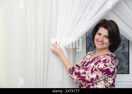 Die Frau legt Tüllklammern an die Vorhänge Stockfoto