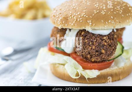 Hausgemachter Falafel Burger (detaillierte Nahaufnahme, selektiver Fokus) auf einem Holztisch Stockfoto