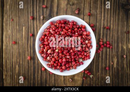 Rosa Pfeffer als detailreiche Nahaufnahme auf einem Vintage Holztisch, selektiver Fokus Stockfoto