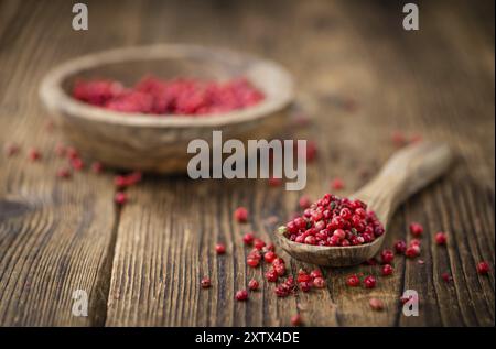 Rosa Pfeffer als detailreiche Nahaufnahme auf einem Vintage Holztisch, selektiver Fokus Stockfoto