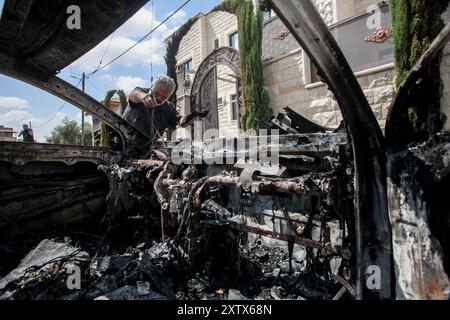 Qalqilya, Palästina. August 2024. Ein Palästinenser inspiziert das zerstörte Auto, nachdem es von jüdischen Siedlern im Dorf JIT in der Nähe von Qalqilya im nördlichen besetzten Westjordanland angegriffen wurde. Jüdische Siedler griffen das palästinensische Dorf JIT an und verwüsteten den Ort, brannten Häuser und Autos in Brand und zerstörten öffentliches Eigentum, töteten einen Palästinenser und verletzten Dutzende. Quelle: SOPA Images Limited/Alamy Live News Stockfoto