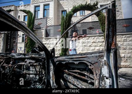 Qalqilya, Palästina. August 2024. Ein Palästinenser neben einem zerstörten Auto gesehen, nachdem es von jüdischen Siedlern im Dorf JIT in der Nähe von Qalqilya im nördlichen besetzten Westjordanland angegriffen wurde. Jüdische Siedler griffen das palästinensische Dorf JIT an und verwüsteten den Ort, brannten Häuser und Autos in Brand und zerstörten öffentliches Eigentum, töteten einen Palästinenser und verletzten Dutzende. Quelle: SOPA Images Limited/Alamy Live News Stockfoto