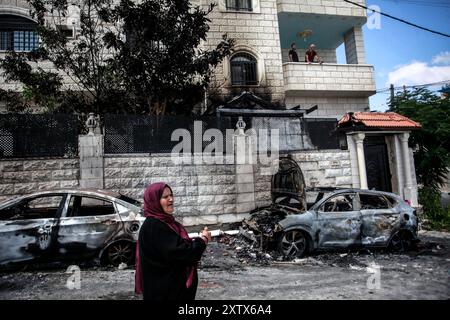 Qalqilya, Palästina. August 2024. Eine Palästinenserin wird vor ihrem zerstörten und verwüsteten Haus gesehen, nachdem es von jüdischen Siedlern im Dorf JIT in der Nähe von Qalqilya im nördlichen besetzten Westjordanland angegriffen wurde. Jüdische Siedler griffen das palästinensische Dorf JIT an und verwüsteten den Ort, brannten Häuser und Autos in Brand und zerstörten öffentliches Eigentum, töteten einen Palästinenser und verletzten Dutzende. Quelle: SOPA Images Limited/Alamy Live News Stockfoto