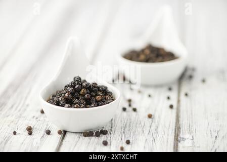 Erhaltene schwarze Pfefferkörner auf hölzernem Hintergrund, selektiver Fokus, Nahaufnahme Stockfoto