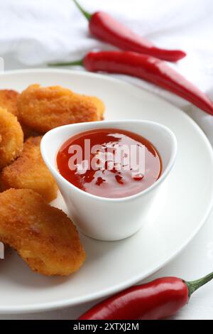 Chili-Sauce und Hähnchennuggets auf weißem Tisch Stockfoto