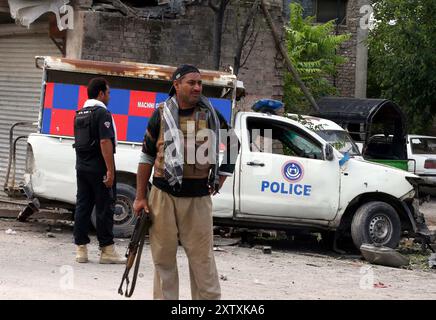 Ansicht des Standorts nach der Explosion, während Sicherheitsbeamte am Freitag, den 16. August 2024, zur Inspektion an der Warsak-Straße in Peshawar absperrten. Mindestens fünf Personen, darunter zwei Polizeikräfte, wurden bei einer Explosion an der Warsak-Straße im Gebiet PIR Bala verletzt. Laut Polizei war das Ziel der Explosion ein Polizeifahrzeug. Arshad Khan, Polizeichef der Warsak Road Superintendent of Police (SP), sagte, dass das Polizeifahrzeug infolge der „ferngesteuerten“ Explosion beschädigt worden sei. Stockfoto