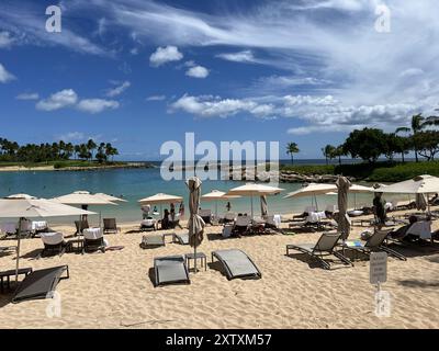 Usa. Juli 2024. Sandstrand im Four Seasons Oahu Hotel mit Liegestühlen und Sonnenschirmen mit Blick auf ruhiges Wasser und Palmen unter blauem Himmel, Oahu, Kapolei, Hawaii, 26. Juli, 2024. (Foto: Smith Collection/Gado/SIPA USA) Credit: SIPA USA/Alamy Live News Stockfoto