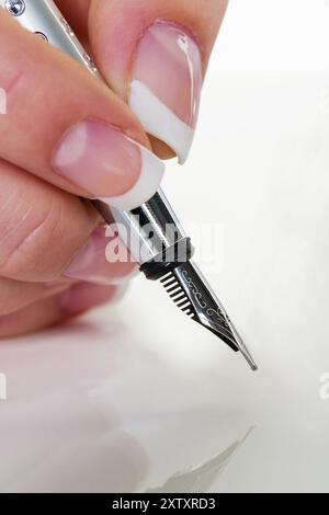 Die Hand einer Frau schreibt mit einem Füllfederhalter, Vertrag, Unterschrift, Vereinbarung, Studio Stockfoto