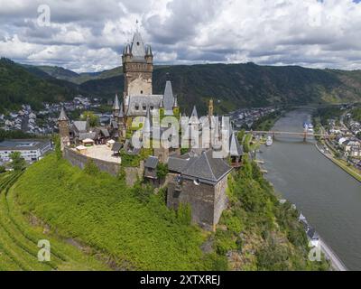 Mittelalterliche Burg auf einem Hügel mit Blick auf einen Fluss und eine Stadt, eingebettet in grüne Natur und umgeben von Bergen unter einem bewölkten Himmel, Luftsicht, Reichs Stockfoto