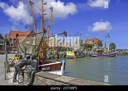 Der Hafen von Neuharlingersiel, Norddeutschland, Ostfriesland, Fischerdenkmal vor Fischerbooten, Neuharlingersiel, Niedersachsen, Bundesrepublik Deutschland Stockfoto