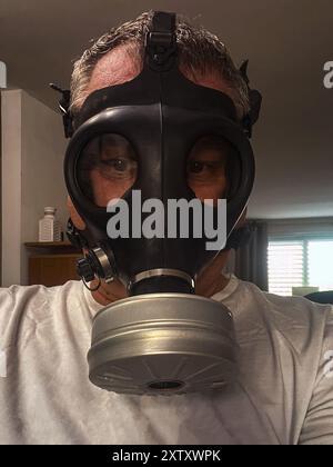 Ein Mann in einer schwarzen Gasmaske in einer Wohnung. Stockfoto