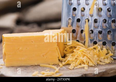 Teil des geriebenen Cheddar-Käse auf rustikalen hölzernen Hintergrund Stockfoto