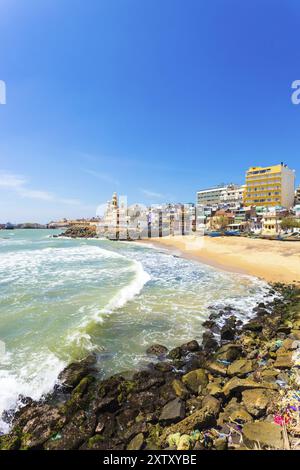 Kanyakumari, Indien, 22. Februar 2015: Bunte Häuser und große Betonhotels säumen einen kleinen Strand nahe der St. Arokiyanathar Alayam Kirche im Süden Stockfoto