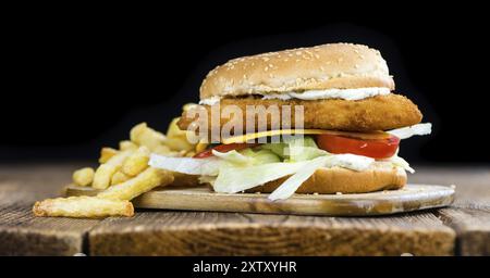 Hausgemachter Fisch Burger (Nahaufnahme, selektiver Fokus) auf einem Holztisch Stockfoto