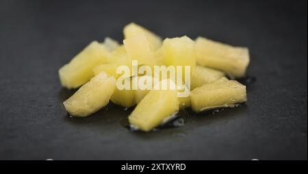 Teil der konservierten Ananas (gehackt) als detaillierte Nahaufnahme auf einer Schieferplatte, selektiver Fokus Stockfoto