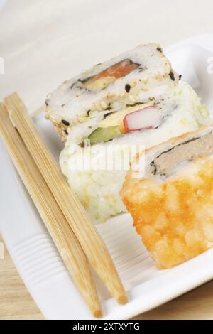 Gemischte Sushi-Brötchen auf einem weißen Teller mit Holzstäbchen. Mit Kopierraum. Selektiver Fokus Stockfoto