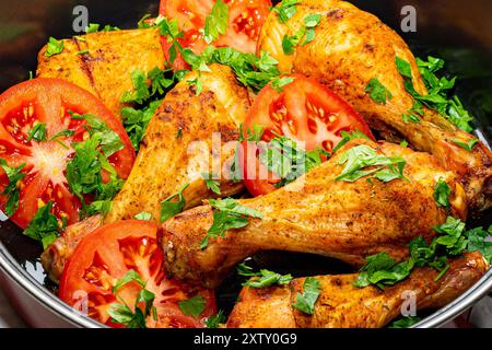 Gebackene Hähnchenschenkel mit frischen Tomaten und Kräutern. Stockfoto