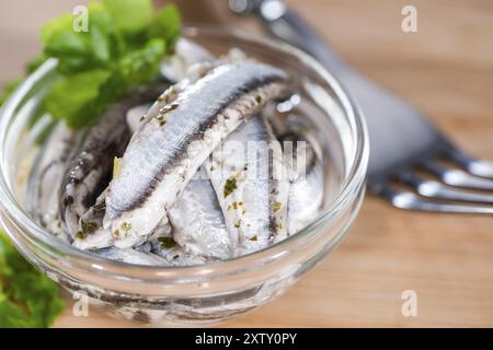 Eingelegte Anchovis mit Kräutern (Nahaufnahme) auf hölzernen Hintergrund Stockfoto