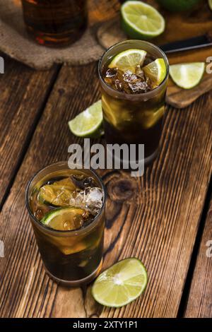 Cuba Libre Longdrink mit Stücken von frischen Limetten und crushed-Ice auf hölzernen Hintergrund Stockfoto