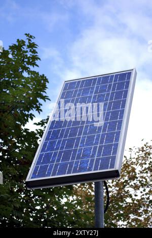Sonnenkollektor vor einem Baum und blauem Himmel Stockfoto