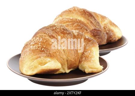 Zwei Croissants serviert auf dunklen braunen keramisches Geschirr, isoliert auf weiss Stockfoto