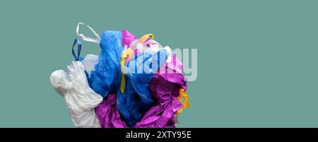 Ein Haufen leerer Müllsäcke in verschiedenen Farben. Abfallsortierungs- und Recyclingkonzept. Kopierbereich. Künstlerisches Bild. Einfarbiger Pastellhintergrund Stockfoto