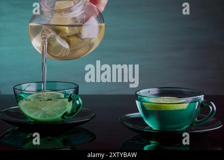 Zitronentee wird in Tassen aus der Teekanne gegossen. Stockfoto