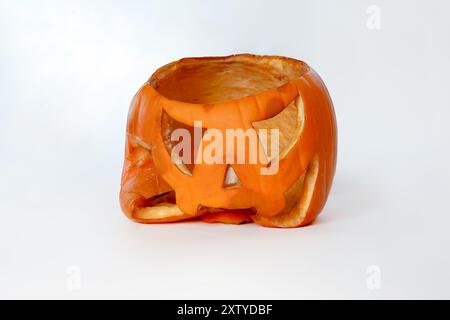 Eine zusammengebrochene Jack-o'-Laterne mit einem sich verschlechternden Gesicht auf weißem Hintergrund, Ende der Saison Stockfoto