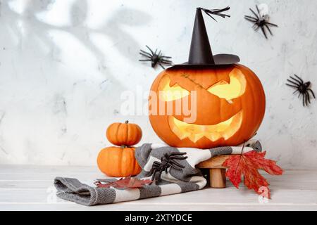 Glühend freundlich geschnitzter Halloween Kürbis in Hexenhut und Schal, weißer Hintergrund Stockfoto