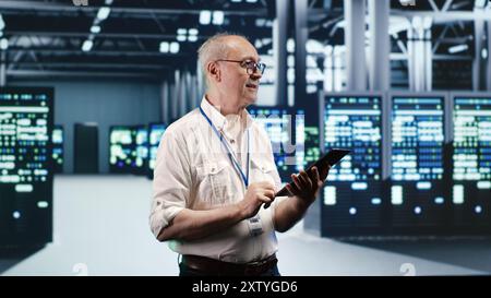 Akribische IT-Profis, die sich in einem Netzwerk von Rackmounts in einem industriellen Server-Hub bewegen. Mitarbeiter mit Laptop für fehlerfreien Betrieb, Optimierungen und Wartung im Rechenzentrum Stockfoto