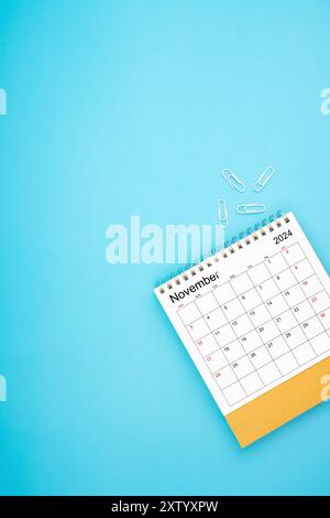 Schreibtischkalender für November 2024 und weiße Büroklammer auf hellblauem Hintergrund Stockfoto