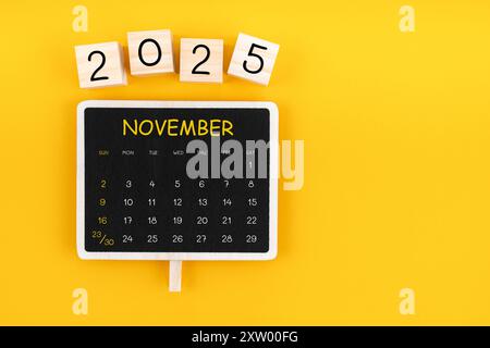 Kalender für November 2025 in schwarzem Schwarzen Tafel mit Kopierraum auf gelbem Hintergrund. Stockfoto