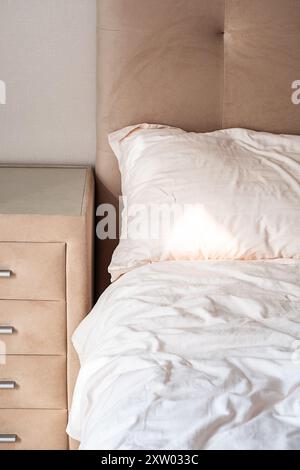 Gemütliches Schlafzimmer mit beigefarbenem Kopfteil und Kommode. Stockfoto