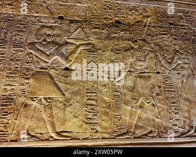 Das Mauerrelief des Pharoah Ptolemäus, der Horus und Hathor opferte, im Tempel des Horus in Edfu, erbaut während der ptolemäischen Ära zwischen 237 und 57 v. Chr. in der Nähe von Assuan, Ägypten Stockfoto