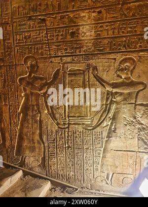 Priets mit der heiligen Barke von Horus, dem Falkengott, dargestellt in einem Basrelief im Tempel des Horus in Edfu, der während der ptolemäischen Ära zwischen 237 und 57 v. Chr. in der Nähe von Assuan, Ägypten, erbaut wurde Stockfoto